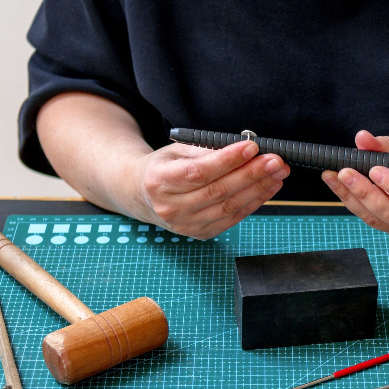 Woman is working with silver ring on a table with various tools and materials in jewelry workspace. Woman is working with silver ring on a table with various tools and materials in jewelry workspace.